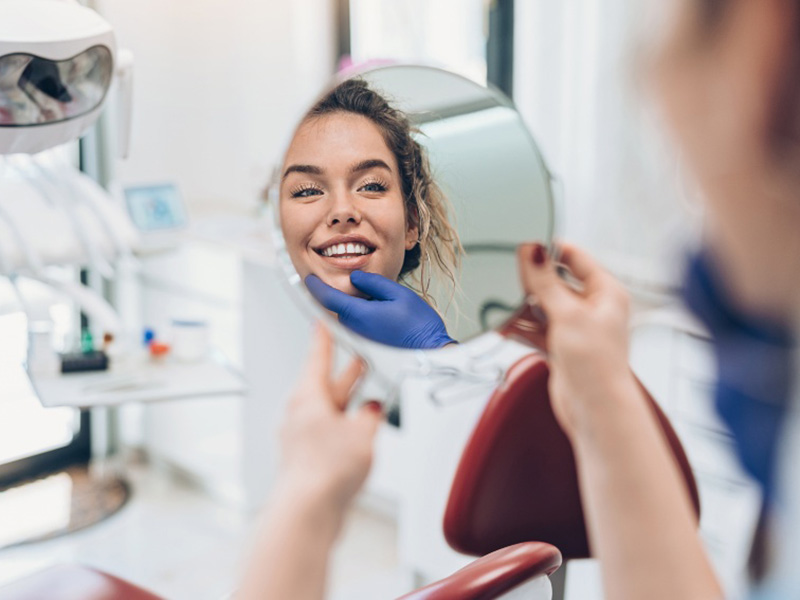 a patient checking her teeth in the mirror